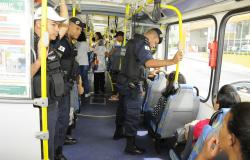 Três guardas municipais acompanham viagem de ônibus durante o dia. 