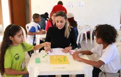 Alunos jogam jogos de tabuleiro acompanhados por adulta.