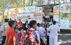 Cerca de dez alunos fazem fila para ter acesso ao Telecentro Móvel, que dá acesso a internet, durante o dia. Outros dois cidadãos estão ao redor do veículo. 
