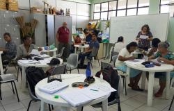 Cerca de nove alunos do programa de Educação de Jovens e Adultos  sentados em mesas tendo aulas de arte no Centro de Referência da Pessoa Idosa