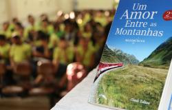 Em primeiro plano, livro "Um amor entre as montanhas". Ao fundo, crianças em desfoque.
