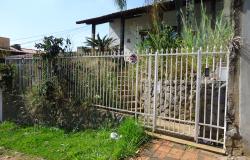 Casa com cerca branca, matagal tampando a entrada