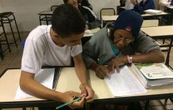 Jovem aluno e mulher de idade que fazem parte do Programa de Educação de Jovens e Adultos do Barreiro estudam sentados.