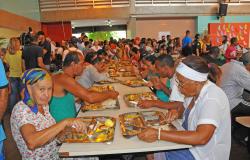 Mais de trenta pessoas das mais diversas idades almoçam em um Restaurante Popular. 