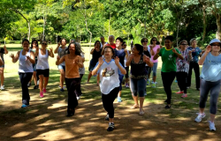 Cerc de onze pessoas praticando dança chinesa rejuvenescedora em local com muito verde no Buritis