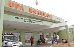 Fachada da UPA Barreiro, com viatura  da Guarda Municipal e sete usuários, durante o dia.