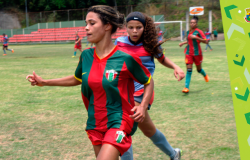 Três garotas jogam futebol.