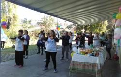 Cerca de 10 usuários fazem Liang Gong em área coberta; ao lado, mesa com refrigerantes e quitutes.