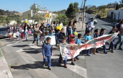 Mais de vinte crianças com menos de sete anos, acompanhadas de professores, nas ruas da Pampulha com cartaz sobre a Semana de Educação Infantil