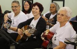 Grupo de idosas tocam violão.