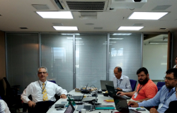 Cinco funcionários da Prodabel em reunião, sentados em uma mesa. 