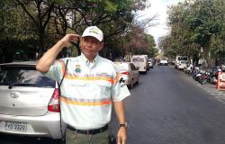 Agente de trânsito da BHTrans em rua com movimento de carros durante o dia. 