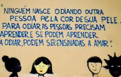Na parte de baixo de uma parede foram desenhadas quatro pessoas, duas delas negras, uma branca e uma com o rosto amarelo. Acima, os dizeres: "Ninguém nasce odiando outra pessoa pela cor de sua pele. Para odiar as pessoas precisam aprender, e se podem aprender odiar, podem ser ensinadas a amar.