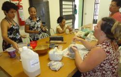 Cinco mulheres pintam cerâmica em torno de uma mesa. 