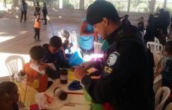 Guarda municipal orienta crianças sobre a montagem de pipas.