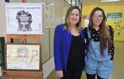 Duas mulheres ao lado de desenhos coloridos em exposição. 