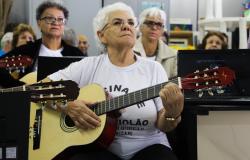 Idosa está sentada tocando violão