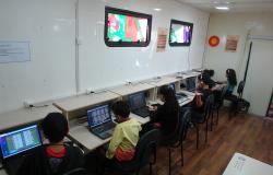 Cinco crianças estão sentadas à frente de notebooks do Projeto Conexão Aberta.