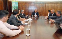O prefeito de Belo Horizonte, Alexandre Kalil, no centro de uma grande mesa de madeira, do Salão Nobre da Prefeitura, ladeado por empresários