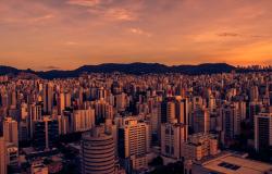 Prédios de Belo Horizonte com Serra do Curral e horizonte ao fundo, foto em sépia avermelhado.