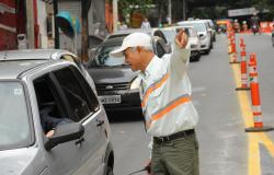 Agente de trânsito orienta carro na rua. 
