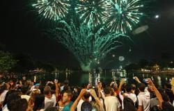 Mais trinta pessoas, na orla da Lagoa da Pampulha, brindam e vêem os fogos de Reveillon.