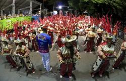 Mais de trinta membros da  Escola de Samba Acadêmicos de Venda Nova, campeã do Carnaval de Belo Horizonte de 2017, tocando instrumentos musicais; a fila da frente tem quatro membros com chocalhos. 