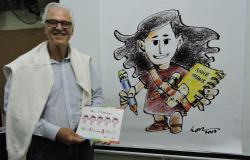 Cartunista LOR posa ao lado de uma caricatura de Anne Frank, menina dos livros que dá nome à escola