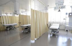 Três macas e três cortinhas acompanhadas de aparelhos médicos em ambiente hospitalar