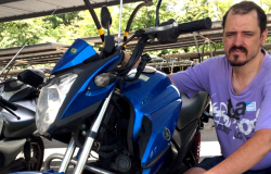 Motorista ao lado de sua moto.