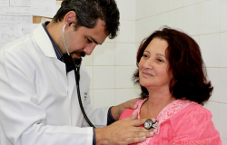 Médico examina coração de paciente com estetoscópio.