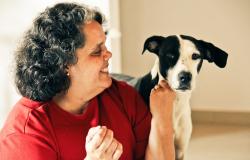 Cidadã sorri para cãozinho que adotou.