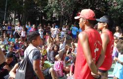 Dois salva-vidas com camisetas vermelhas e bonés acompanham crianças do Programa Escola nas Férias. 