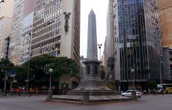 Praça Sete de Setembro com carros passando e prédios, no fim do dia.