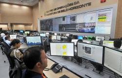 Mais de vinte pessoas em três fileiras, cada uma delas em frente ao computador; à frente, um painel grande de vídeo em uma parede. No alto os dizeres: Centro de Operações da Prefeitura de Belo Horizonte. 