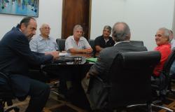 O prefeito de Belo Horizonte, Alexandre Kalil, os secretários municipais de Saúde, Jackson Machado, e de Fazenda, Fuad Noman, e representantes da Maternidade Sofia Feldman, sentados em uma mesa oval, conversando.
